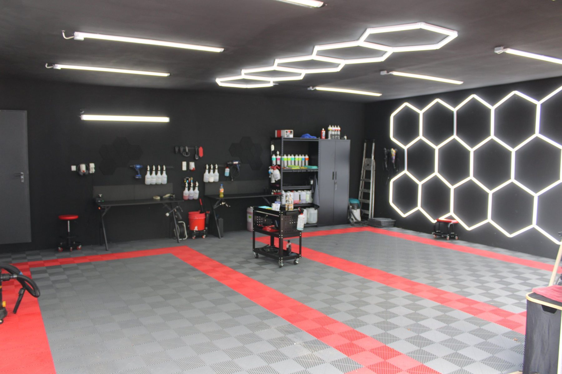 Aufbereitungshalle von Autoaufbereitung Gossmann mit Hexagon-Beleuchtung und rot-grauem Fliesenboden